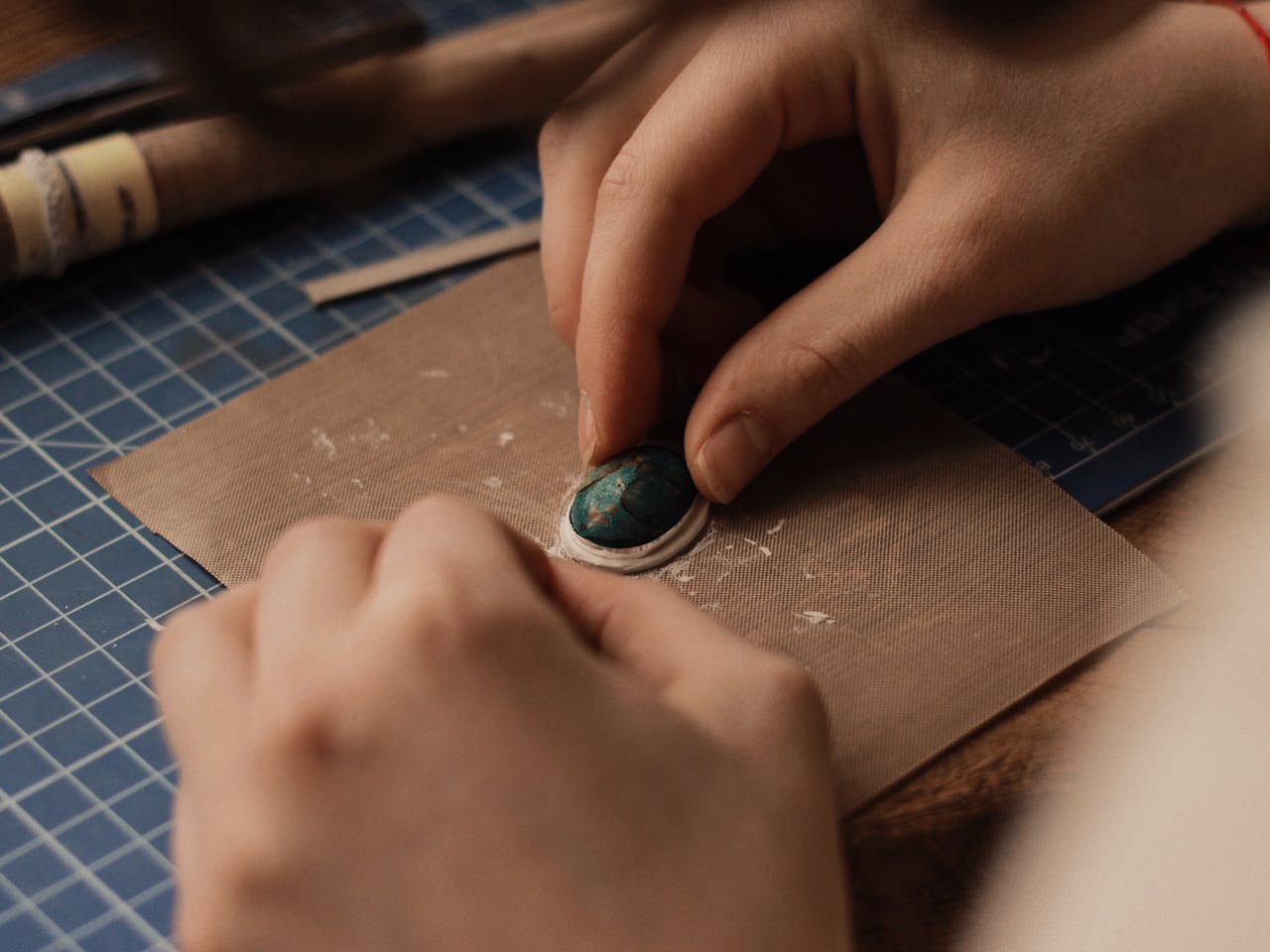 The Art of Drawing Readers In: Your attractive post title goes here Detailed view of hands crafting jewelry with turquoise gemstone, emphasizing precision and artistry.