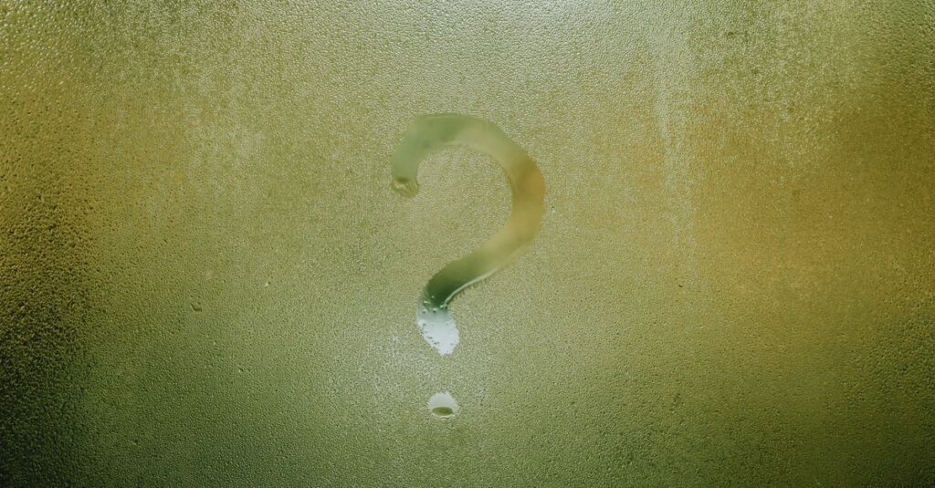 Translucent wet glass window covered with water drops with question mark on surface